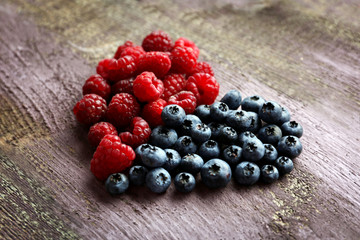 Heart shaped raspberries and blueberries on old wooden background