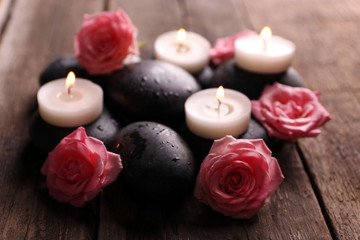 Tenderness relaxing composition with pebbles, roses and candles on wooden background, close up