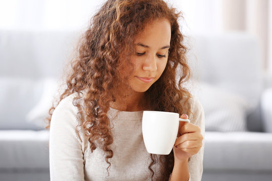 Close up portrait of pretty young woman drinking coffee in the room