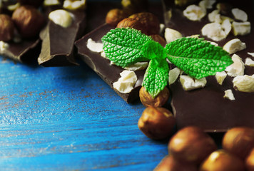 Chocolate pieces with nuts on color wooden background