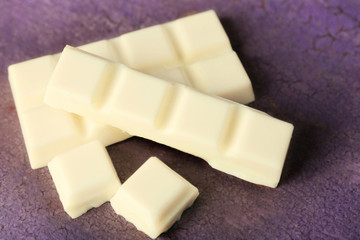 White chocolate pieces on color wooden background