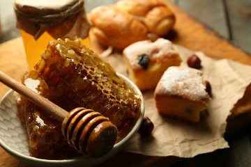 Honeycombs on plate, hot buns on wooden background
