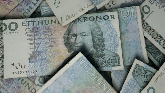 An extreme close up pan of a pile of randomly scattered swedish kronor banknotes