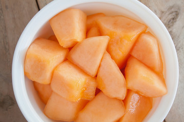 melon slices in white dish on wood table