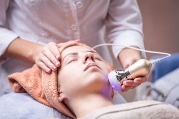 Obraz na płótnie Canvas Young woman receiving facial treatment with electroporation beauty device