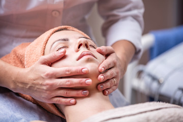 Obraz na płótnie Canvas Young woman in spa salon, beautician performing facial massage