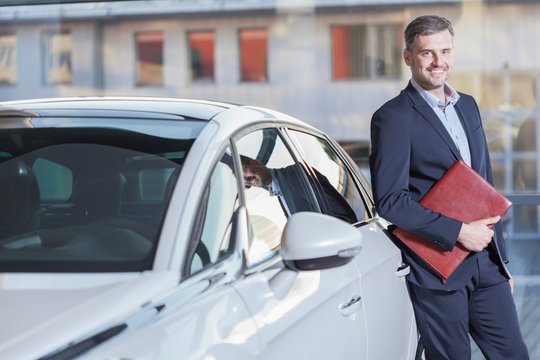 Smiling businessman with new automobile