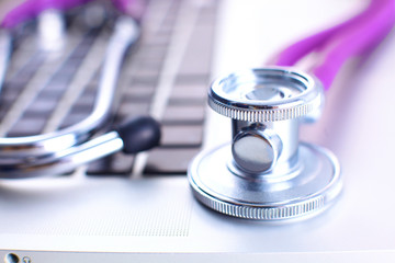 A medical stethoscope near a laptop on a wooden table, on white