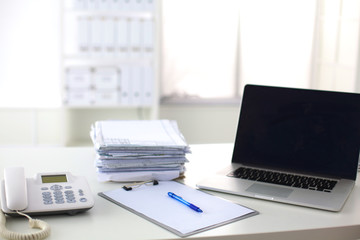 Laptop with stack of folders on table on white background