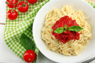 Spaghetti with tomato sauce and cheese on white plate, on color wooden background