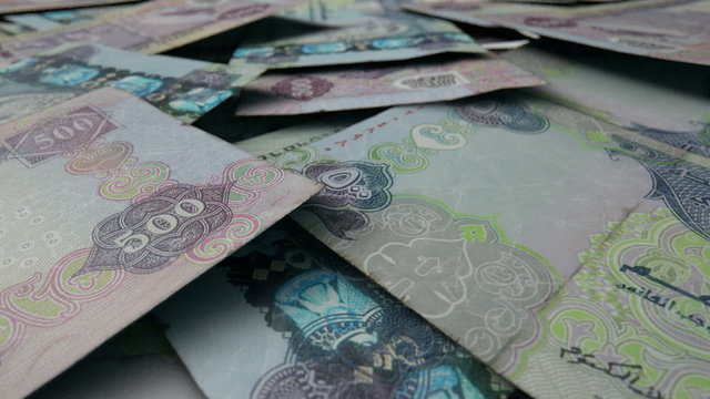 An extreme close up pan of a pile of randomly scattered dirham banknotes