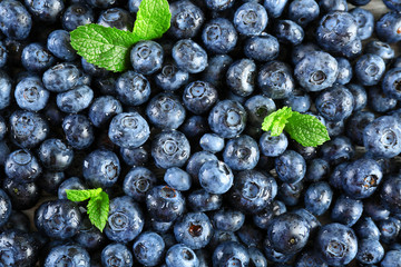 Tasty ripe blueberries with green leaves close up