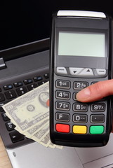 Obraz premium Hand of woman using payment terminal, currencies dollar on laptop in background