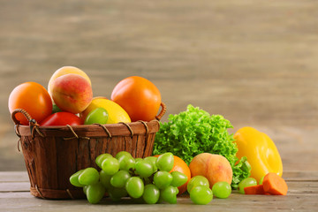 Heap of fresh fruits and vegetables in basket on wooden table close up