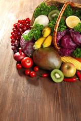 A set of fruit and vegetables in a basket on wooden background