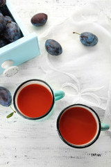 Plum Juice in mugs with fresh fruits