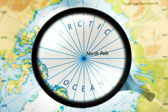 Map, magnifying glass and Arctic ocean on the focus