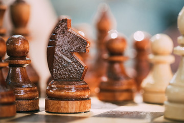 Old Wooden Brown Chess Knight and Pawns Standing On Chessboard