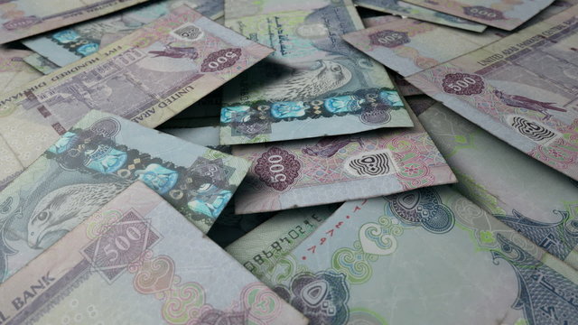 An extreme close up pan of a pile of randomly scattered dirham banknotes