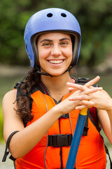 Fototapeta na wymiar A young girl in a white helmet and life jacket navigating through rough water while rafting, emphasizing safety in extreme sports.