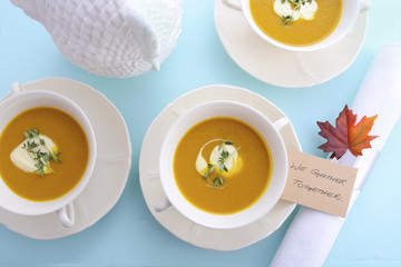 Traditional Thanksgiving pumpkin soup on pale blue table.
