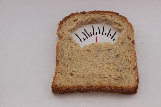 Lose Weight And Whole-grain Bread. Closeup Whole Bread Look Like A Weighing For Weight Control, Concept. Metaphor Photography, Allegory . Fork And Knife Near Weighing Bread For Healthy Lifestyle.