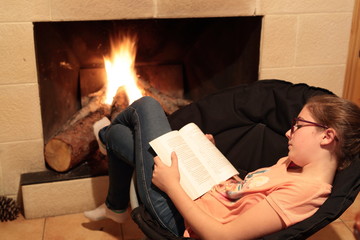girl reading a book beside a fireplace wing