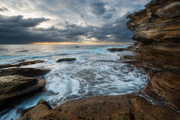 Fototapeta na wymiar Seascape sunrise with unrest sea and grim sky and cliffs