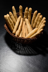 Fresh baked cheese sticks in a wicker wooden basket on black tab