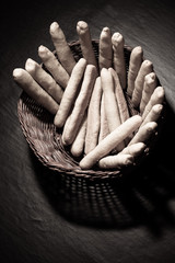 Fresh baked cheese sticks in a wicker wooden basket on black tab