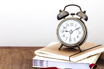 a vintage alarm clock  and books on wooden table with copy space