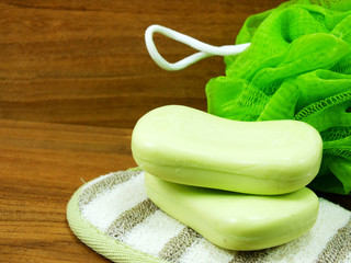 green soap and plastic bath puff on wooden background