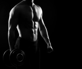 Fototapeta na wymiar Strong, fit and sporty bodybuilder man with a dumbbell in monoch