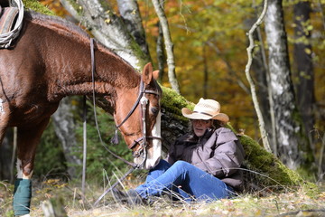 Rast im Wald, Frau mit Westernpferd sitzt vor Birke