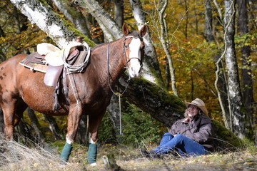 Pause, Frau mit Westernpferd sitzt im Herbstwald