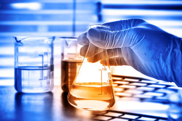 Flask in scientist hand with laboratory background 