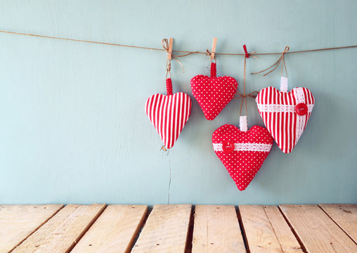 christmas image of fabric red hearts hanging on rope in front of blue wooden background. retro filtered
