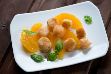 Roasted scallops with orange fillet and green basil, studio shot