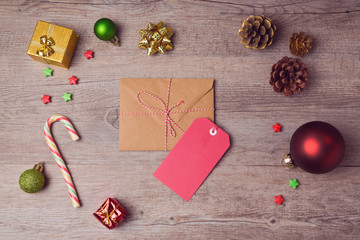 Envelope and gift tag with Christmas decorations on wooden background. View from above