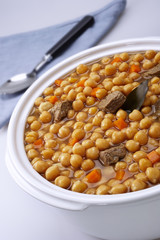 Pot of chickpeas with meat on a white background.