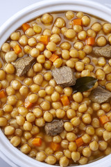 Pot of chickpeas with meat on a white background
