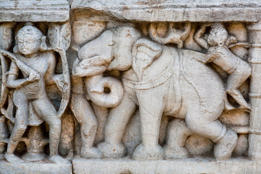 Elephant and a warrior as a details of massive stone bas-relief on the front of historical wall of Hindu temple