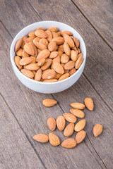 Almonds in white bowl on wooden