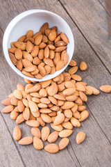 Almonds in white bowl on wooden