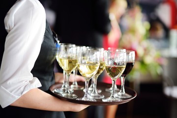 Waitress with dish of champagne and wine glasses