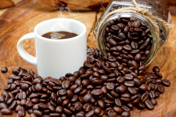 Roasted coffee beans on wood and black coffee.