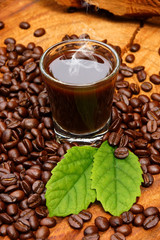 Roasted coffee beans on wood and black coffee.