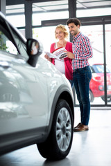 Happy couple  in car showroom
