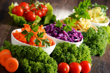 Composition with four vegetable salad bowls on wooden table