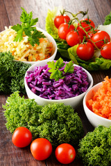 Composition with four vegetable salad bowls on wooden table